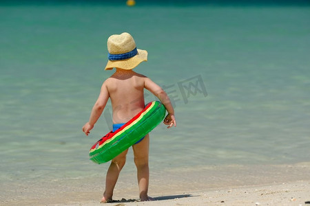 海滩上戴着充气游泳圈的两岁幼儿
