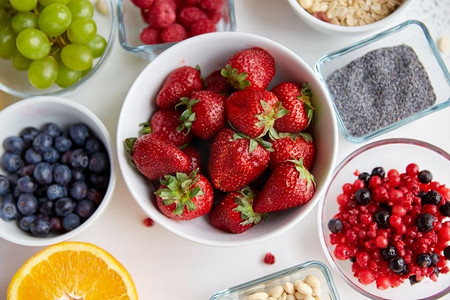 餐桌上的水果摄影照片_健康饮食和饮食理念--把水果和浆果放在餐桌上的碗里。餐桌上盛在碗里的水果和浆果