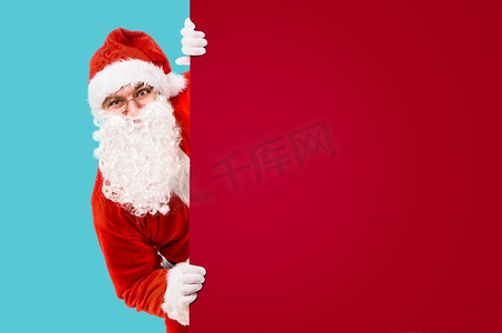 圣诞老人正在五颜六色的广告牌和文案版面外张望。圣诞老人和五颜六色的广告牌