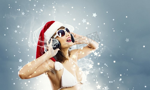 新年晚会。穿着白色比基尼、戴着耳机的圣诞老人女孩