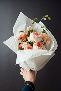 桃粉背景摄影照片_女孩与一束好的桃玫瑰在黑色背景的礼物。美丽的粉红玫瑰