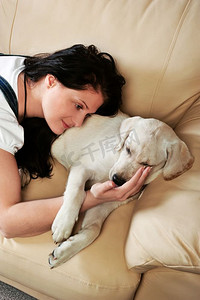 抱着狗摄影照片_抱着狗坐在沙发上的年轻女子
