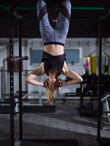 在交叉健身房做腹肌练习的女运动员倒挂在单杠上。正在做腹肌锻炼的女性