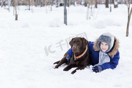 冬季户外男孩摄影照片_学龄儿童与狗在冬季公园。我和我最好的朋友