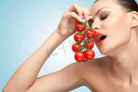 一幅富有创意的肖像，画中一个美丽的女孩在性爱时嘴边放着一串樱桃西红柿。