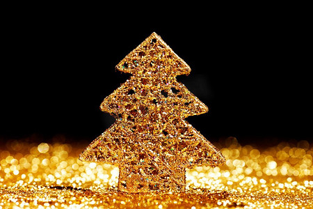 金色闪光摄影照片_美丽的金色装饰圣诞树在金色闪光背景与黑色副本空间