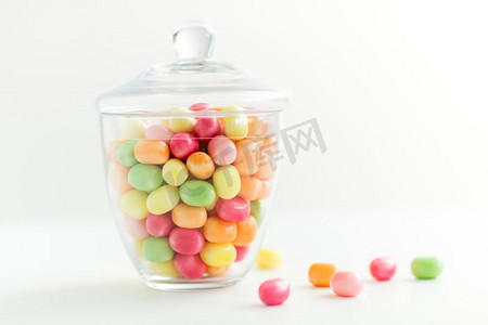 食品，糖果和糖果概念—玻璃罐与五颜六色的糖果滴在白色背景。玻璃罐与糖果滴在白色背景