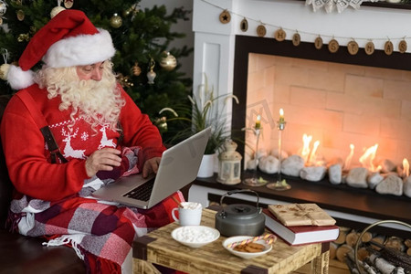 圣诞老人在家中圣诞树附近工作。阅读儿童书信