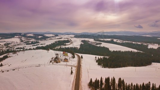 冬季雪山景观。日落多云的天空。空中农村视图的道路通过地平线。喀尔巴阡山脉，贝斯基德山脉