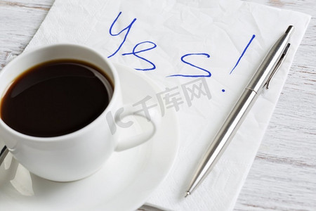 供认摄影照片_是的，在餐巾纸上回答。是的留言写在餐巾和咖啡杯上的木桌上