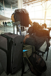 一个拿着很多行李的人坐在机场等飞机。对旅行的期待