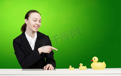 套鸭子摄影照片_年轻女商人与黄色橡胶鸭玩具。女人和鸭子