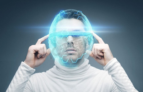 现实和虚拟摄影照片_未来的技术和人的概念-戴着3D眼镜和虚拟头盔的人在蓝色背景上。戴3D眼镜和虚拟头盔的男子