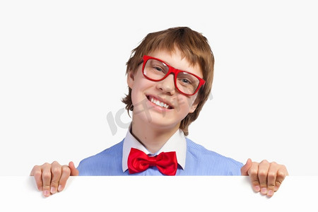 红白色海报摄影照片_戴红眼镜的男孩拿着白色的方块。图片的年轻男孩笑着举行白色广场。广告位