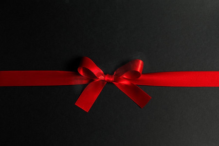 蝴蝶结丝带摄影照片_黑色背景上的红色礼物蝴蝶结。黑色上的红色礼物蝴蝶结
