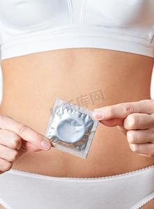 性病摄影照片_穿着内裤的女子拿着避孕套的特写