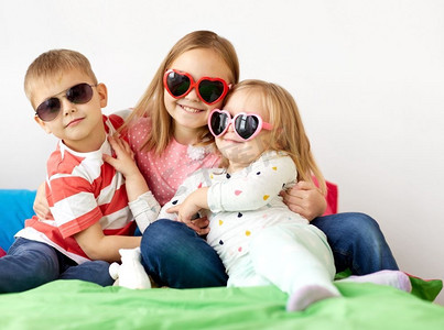 心形太阳镜摄影照片_夏天，情人节和童年的概念-戴着心形太阳镜的小孩子们在家里快乐。家里戴着墨镜的快乐小朋友