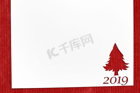 在红色桌子上圣诞卡或新年背景的冷杉树形状剪纸。桌上的冷杉形剪纸