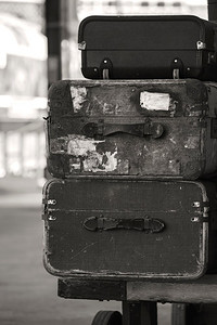 陈旧的老式行李箱堆放在火车站台上。陈旧的古董行李箱堆放在深褐色的火车站台上