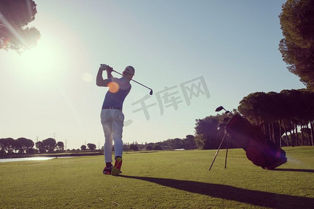在阳光灿烂的早晨，高尔夫球手在球场上用球杆击球。高尔夫球手击球
