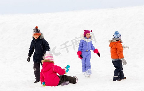 一群小孩子摄影照片_童年，休闲和季节概念—一群穿着冬装的快乐的小孩子在户外玩耍。快乐的小孩子在冬天户外玩耍