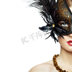 戴着神秘的黑色威尼斯面具的美丽的年轻女子。时尚照片。黑色羽毛化妆面具