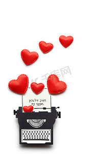 创意情人节礼物概念照片，打字机由纸制成，白色背景上有心形。