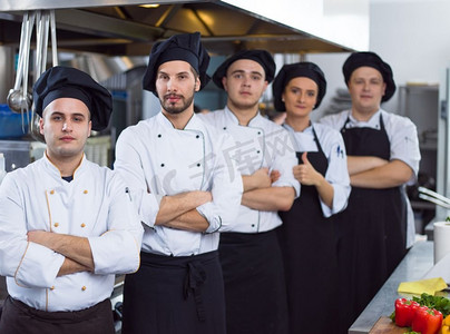 在餐厅的商业厨房里，集体厨师站在一起的肖像。群厨画像