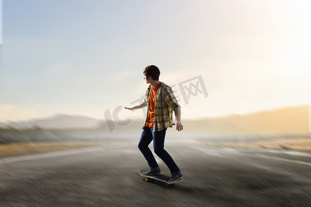 滑板男孩摄影照片_男孩骑滑板。在柏油路上骑滑板的好手