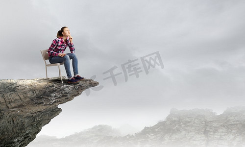 站在顶端。一位穿着休闲服装的年轻女子坐在岩石上的椅子上