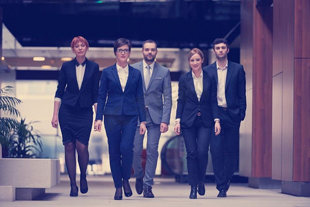 年轻的商务人士团队行走，一群人在现代办公大厅内部