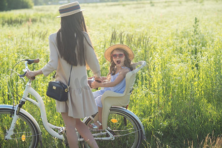 孩子大自然摄影照片_母亲和女儿骑自行车在大自然。夏季活动