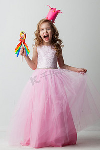 艾莎公主摄影照片_美丽的小糖果公主女孩在冠拿着大棒棒糖和微笑。糖果公主女孩