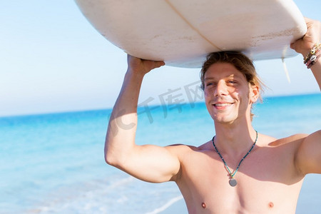 波澜摄影照片_一名年轻的冲浪者在海滩上挥舞着冲浪板。准备好掀起波澜