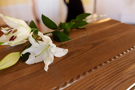 葬礼和哀悼概念-在木棺材盖的白色百合花在葬礼在教堂。百合花木制棺材在葬礼在教堂