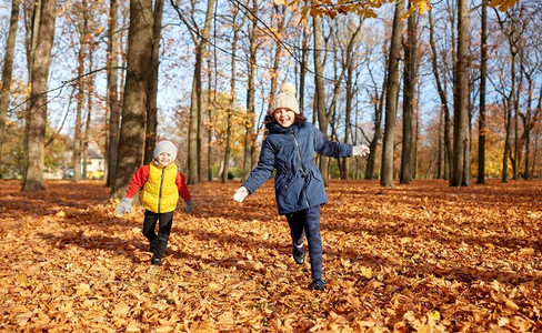 童年，季节和人的概念—快乐的孩子在秋天公园的落叶上奔跑。快乐的孩子在秋天公园跑步