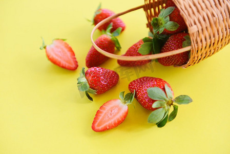 新鲜的草莓在黄色背景/成熟的红草莓采摘在篮子