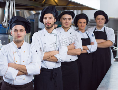 厨卫电器广告摄影照片_在餐厅的商业厨房里，集体厨师站在一起的肖像。群厨画像