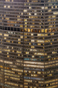蓝色窗户摄影照片_深夜工作的城市概念，商业中心办公楼的窗户立面在夜间，纽约，美国