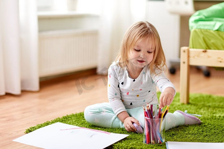 童年，活动和人的概念-快乐的小女孩在家里画蜡笔。快乐的小女孩在家里画着蜡笔