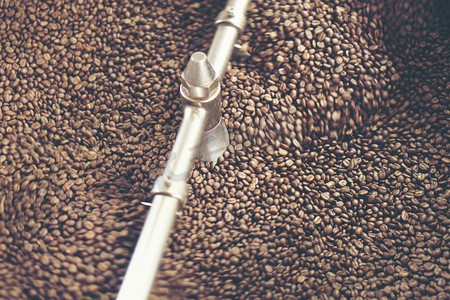 新鲜烘焙芳香咖啡豆在现代咖啡烘焙机，老式过滤器图像