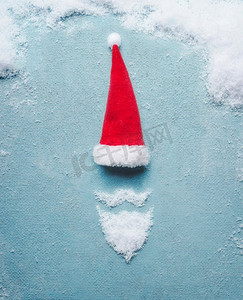 圣诞老人象征用雪和圣诞老人帽子在蓝色背景圣诞卡。创意极简假日概念