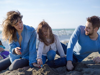 矢矢摄影照片_家庭与小女儿休息和享受在海滩在秋天的一天。在秋日享受矢量化的年轻幸福家庭