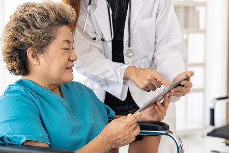亚洲自信医生用数字平板表达对坐在轮椅上的老年女性患者的健康担忧