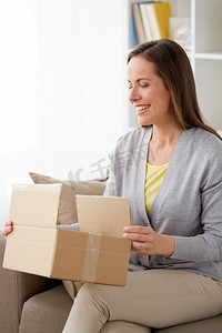 快递、邮件和人的概念-微笑的中年妇女在家里打开包裹盒子。微笑的女人在家里打开包裹盒子