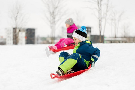 童年，雪橇和季节概念—快乐的小孩子在冬天滑下雪山的雪橇。冬天，孩子们在雪橇上滑下雪山