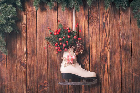 木质墙上挂着圣诞装饰的溜冰鞋。圣诞装饰溜冰鞋