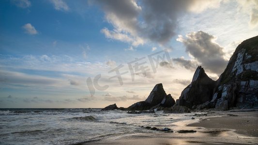 Westcombe海滩美丽的日落风景图象在德文郡英格兰与锯齿状岩石在海滩和惊人的云形成