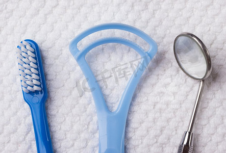 口腔卫生健康概念。特写牙齿工具蓝色牙刷镜子和舌头清洁剂在白色毛巾