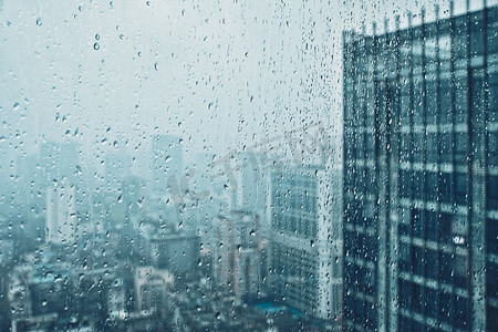 雨水滴在窗口玻璃纹理与摩天大楼在背景。雨点落在窗户上